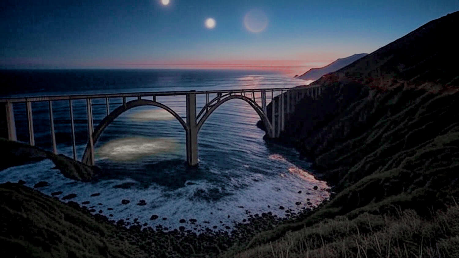 Surfing the Interstates Chapter 11 - ZIP!: Bixby Bridge on Big Sur California coast at twilight with mysterious lights in the starlit sky above the Pacific Ocean. Unexplained phenomena off the coast reveal the ocean's memory in a moment beyond rational und